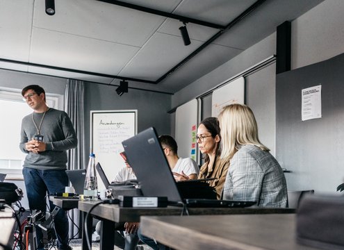 Neue Höfe Seminar- oder Vortragsraum, ein Mann hält einen Vortrag vor mehreren Zuhörern mit Laptops. Macher sein an motivierenden Arbeitsorten