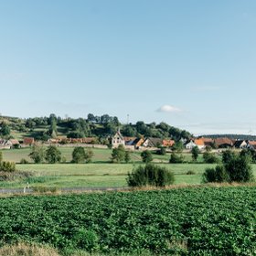 Erlebnisorte Neue Höfe, Neuhoff/Zenn, Panoramaaufnahme einer idyllischen Landschaft mit einem kleinem Ort mit Stadtmauer, viel Wiesen und Bäumen