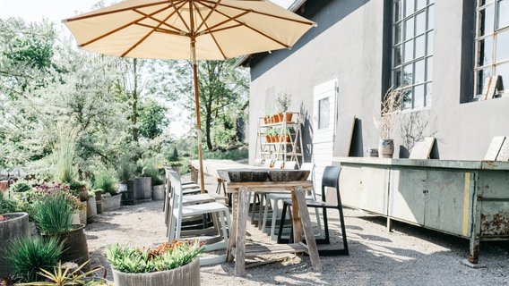 Moderne und idyllische Außenterrasse des Wirtshaus am Hammerhof, Kies-Terrasse mit modernem Mobiliar, üppige Begrünung, entspannte Atmosphäre, Neue Höfe 