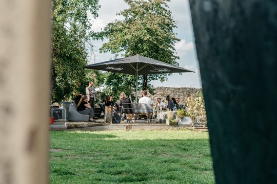 Kraft tanken in der Natur. Menschen sitzen im Freien unter einem Sonnenschirm und unterhalten sich.