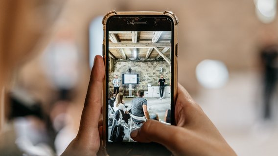 Veranstaltung Gutshof Neun. Ein Smartphone macht ein Foto einer Präsentation.