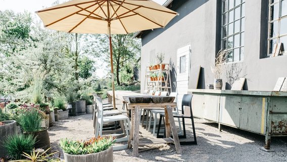 Moderne und idyllische Außenterrasse des Wirtshaus am Hammerhof, Kies-Terrasse mit modernem Mobiliar, üppige Begrünung, entspannte Atmosphäre, Neue Höfe 