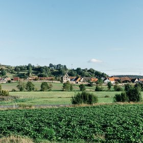 Erlebnisorte Neue Höfe, Neuhoff/Zenn, Panoramaaufnahme einer idyllischen Landschaft mit einem kleinem Ort mit Stadtmauer, viel Wiesen und Bäumen